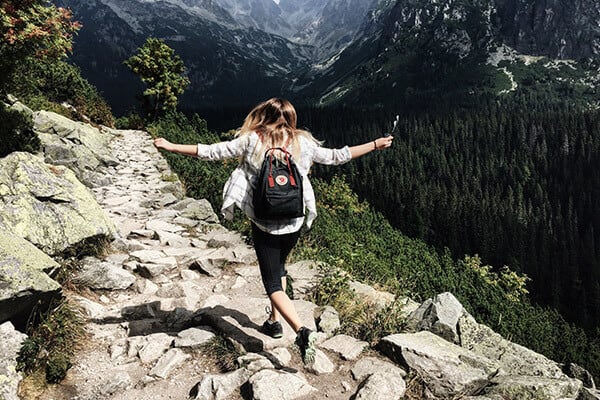 woman running in the mountains with her arms in the air
