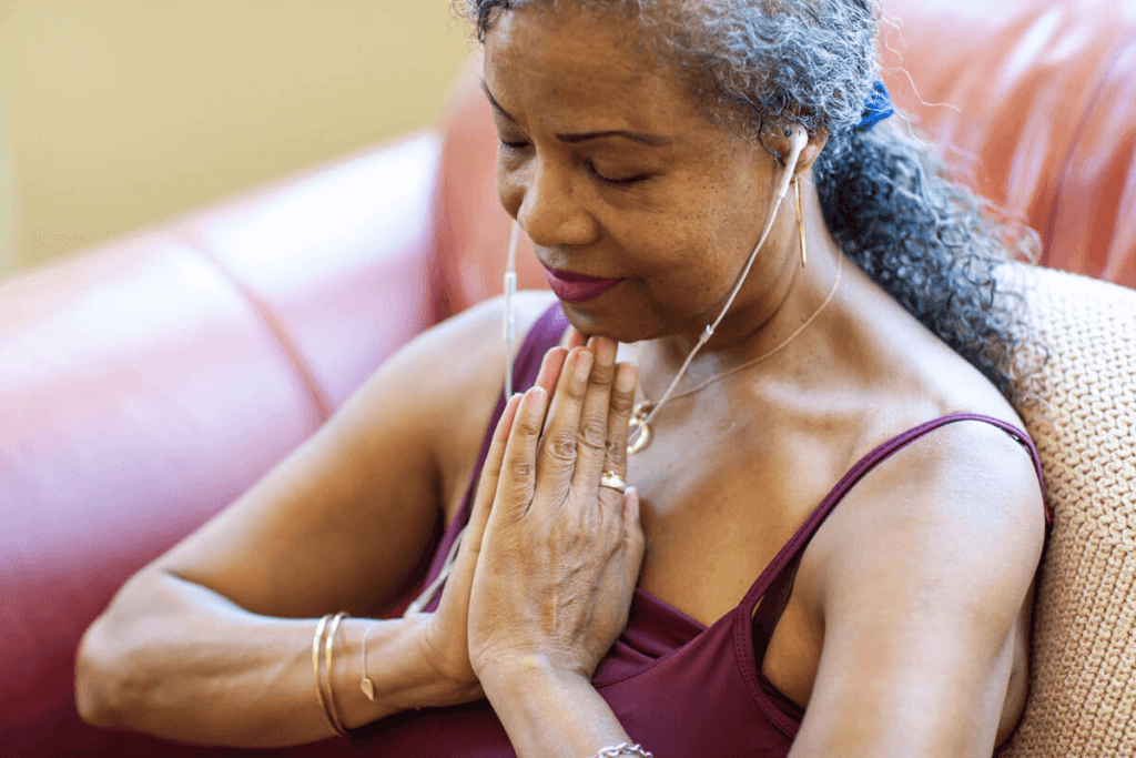 woman with her hands closed with headphones listening to breathing app