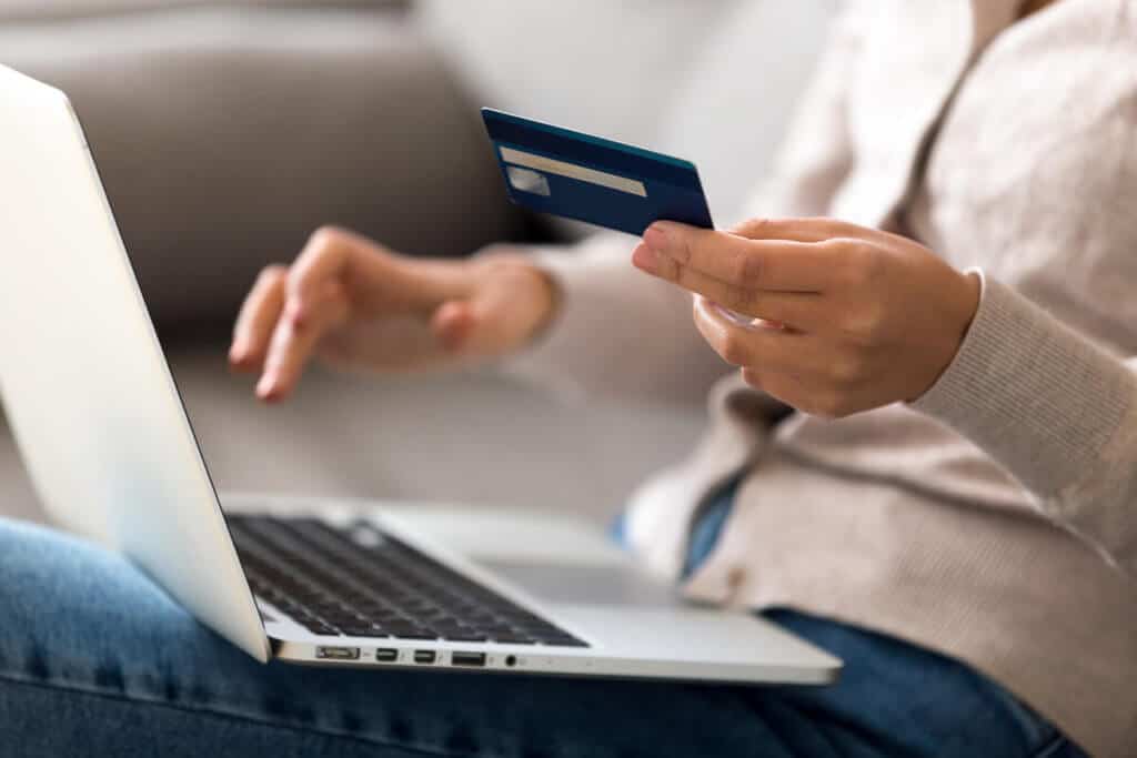 close up of person holding card and paying online on laptop