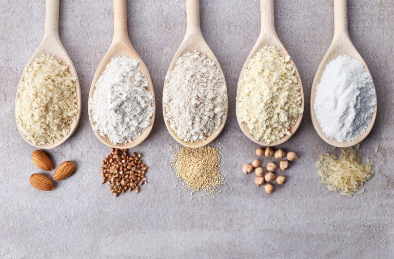 multiple spoons filled with powdered grains, representing the gluten-free diet