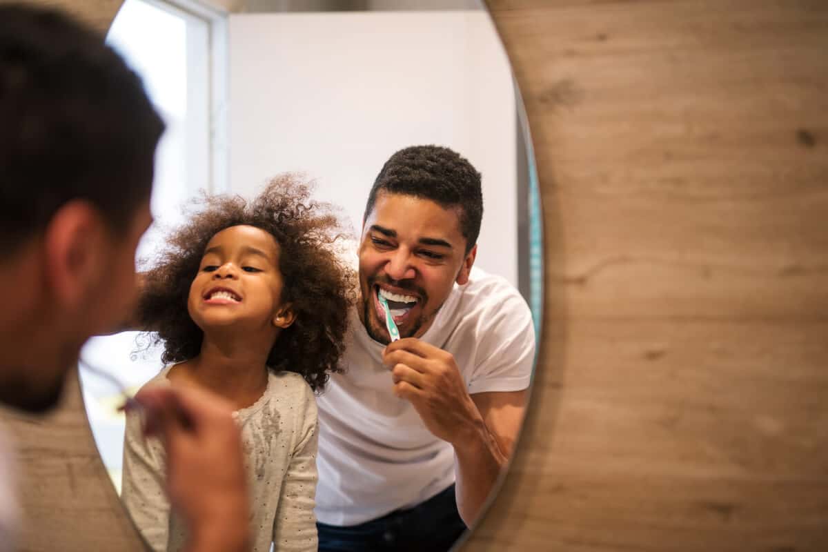 A man and a child brushing their teeth 