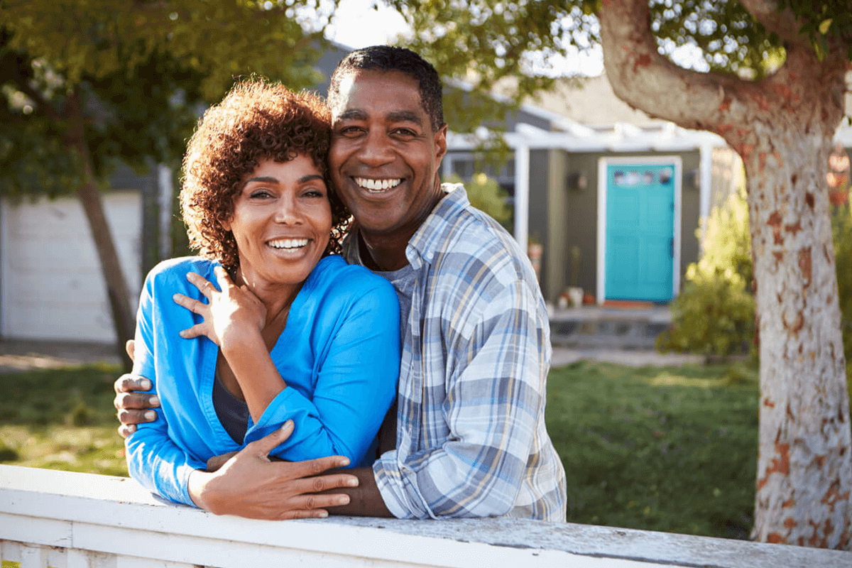 Mature couple looking over the fence in a front yard.