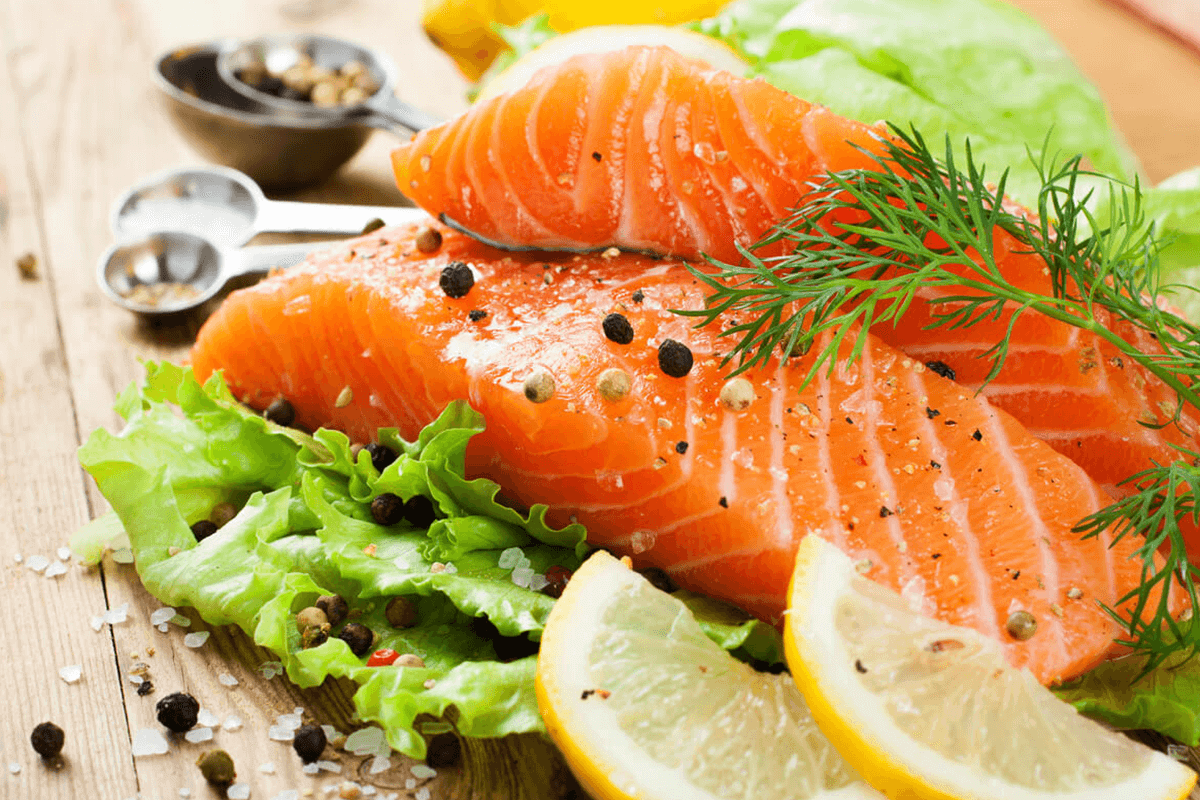 Fresh salmon with herbs and spices over a wooden cutting board.