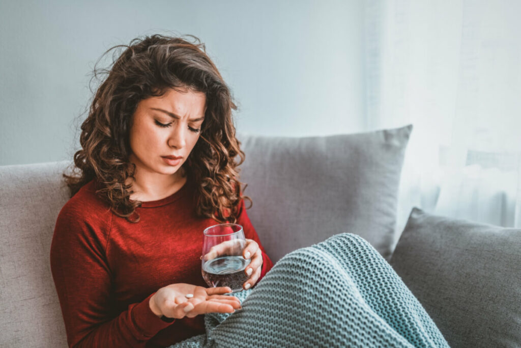woman sitting on a couch taking a supplement