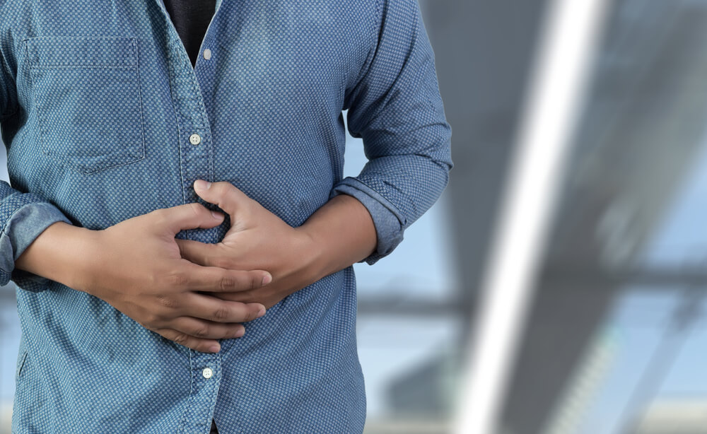 A man holding his stomach because he has gut issues