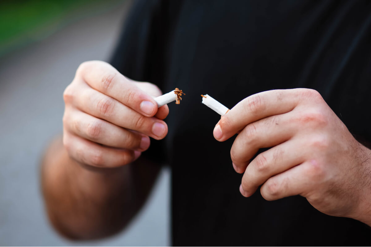 man breaking a cigarette in half