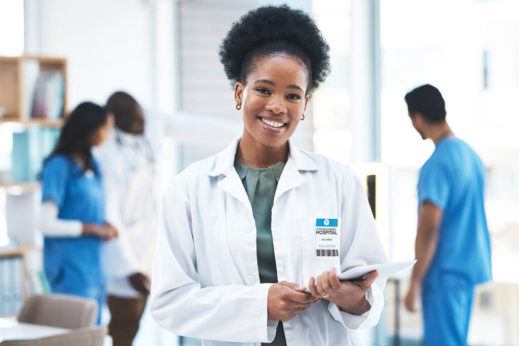 A woman in a white coat is holding a tablet, suggesting she is possibly engaged in a medical or research-related task.